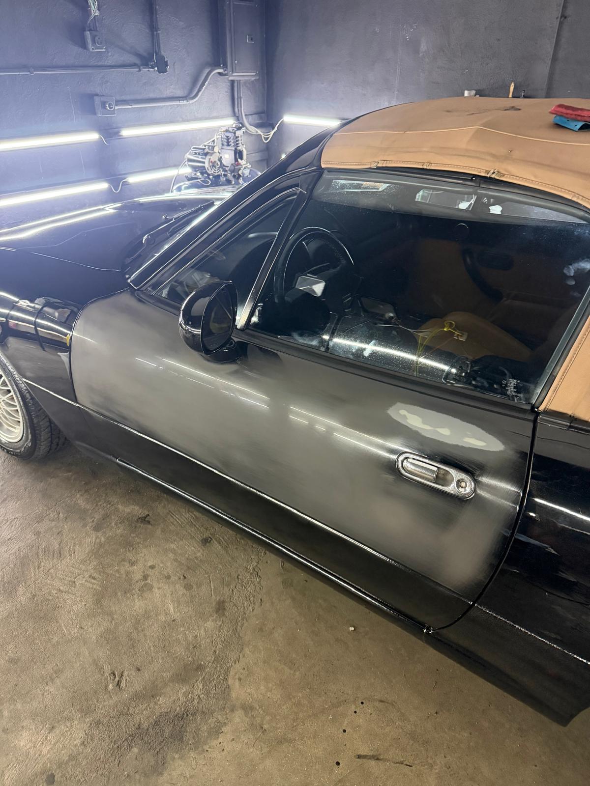 Paint correction in progress on a black Mazda Miata
